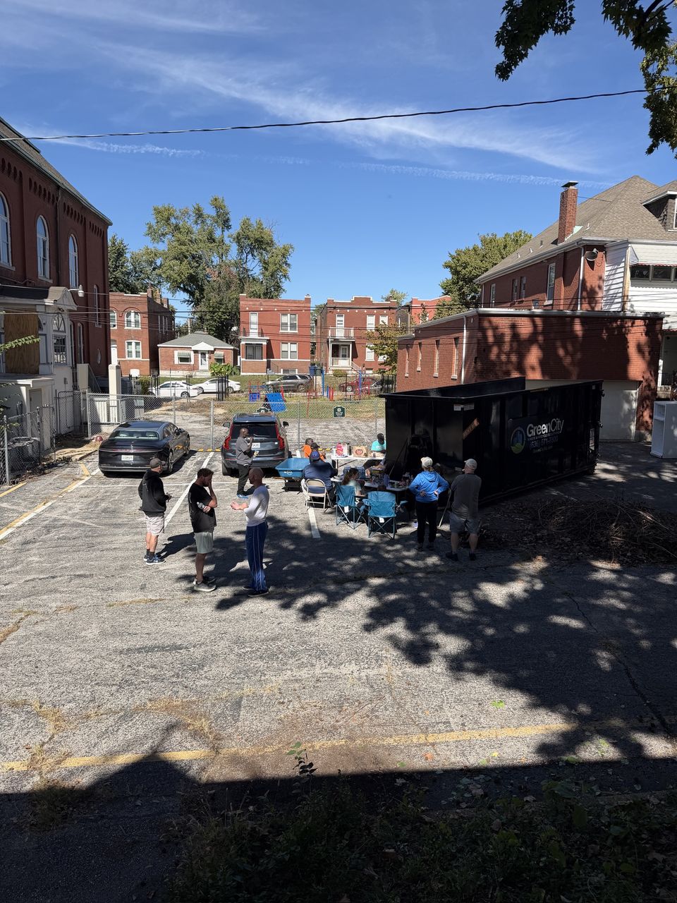 Volunteers eating lunch at a folding table in the church lot after a work morning
