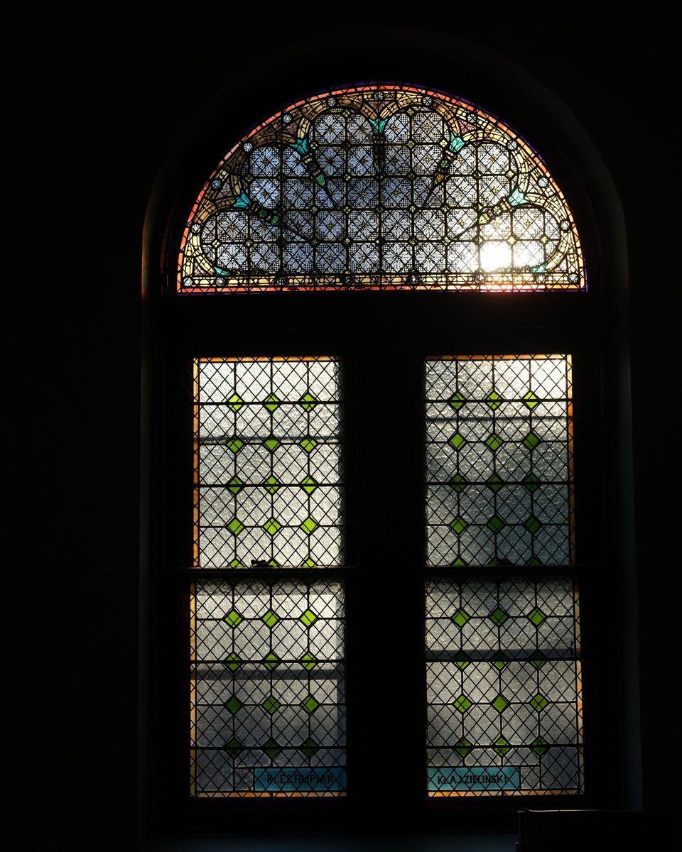 Arched stained glass window in the sanctuary with afternoon light coming through